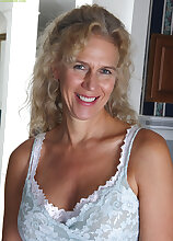 Busty blonde housewife Cally Jo fingers her pussy on the sofa.